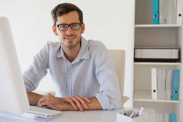 Casual, homem negócios, sorrindo, câmera, em, seu, escrivaninha
