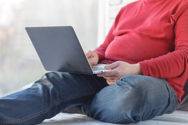 Casual homem sentado e trabalhando com o laptop no chão de madeira