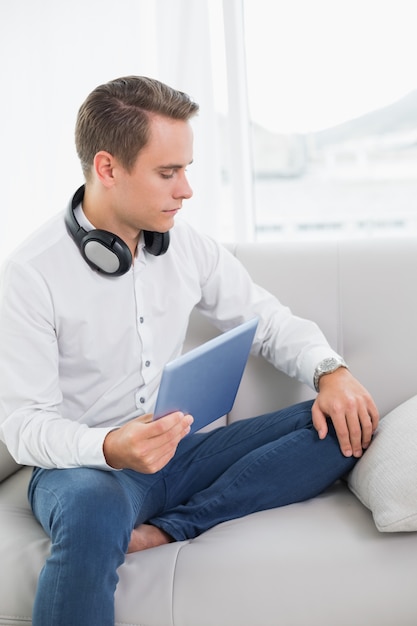 Casual jovem serio usando tableta digital no sofá