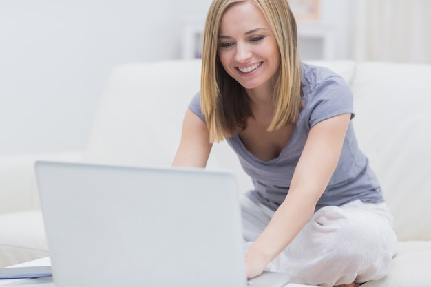 Casual mujer feliz usando la computadora portátil en casa