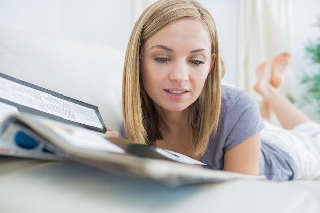 Casual mujer leyendo revista mientras se está acostado en el sofá