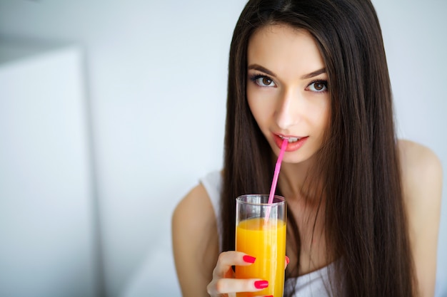 Casual mujer sonriente sosteniendo un vaso de jugo de naranja