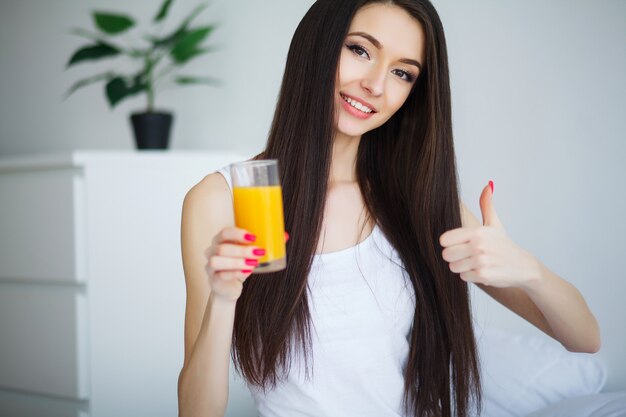 Casual mujer sonriente sosteniendo un vaso de jugo de naranja