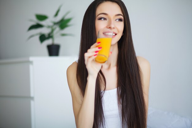 Casual mujer sonriente sosteniendo un vaso de jugo de naranja