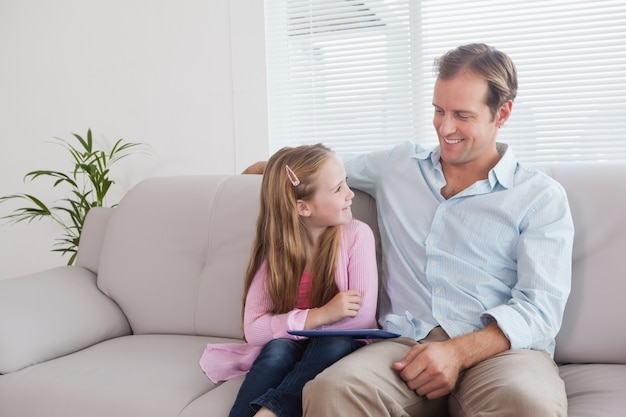 Casual padre e hija usando tableta en el sofá