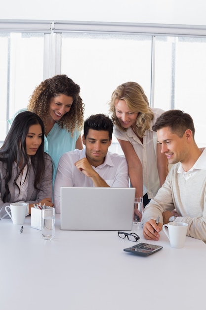 Casual sorridente equipe de negócios tendo uma reunião usando laptop