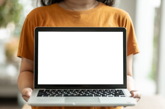 Casual sosteniendo y mostrando la computadora portátil con una pantalla en blanco en la cafetería