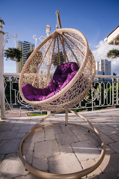 casulo de cadeira pendurada com uma almofada roxa no terraço de verão do restaurante