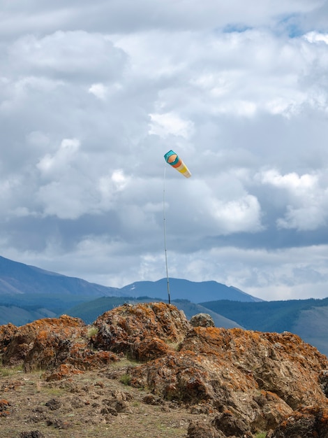 Cata-vento, designador de vento contra as montanhas azuis. Visão vertical.