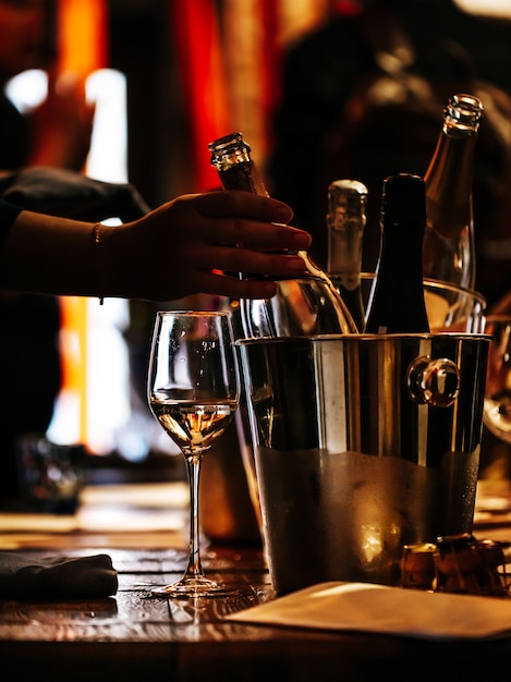 Cata de vinos: hay una copa de vino en una mesa de madera y un cubo de plata para enfriar vinos.