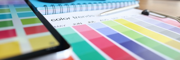 Catálogo con muestras de color y tableta digital en primer plano de la mesa
