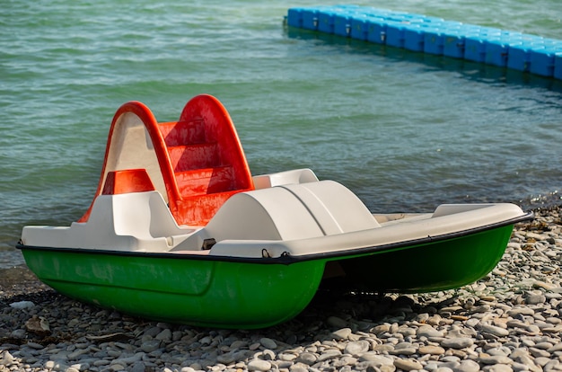 Catamarã verde em uma praia de seixos na perspectiva do mar