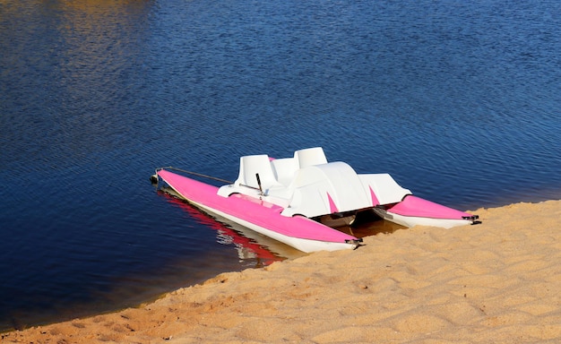 Catamarán Whitepink en la orilla arenosa del lago en verano