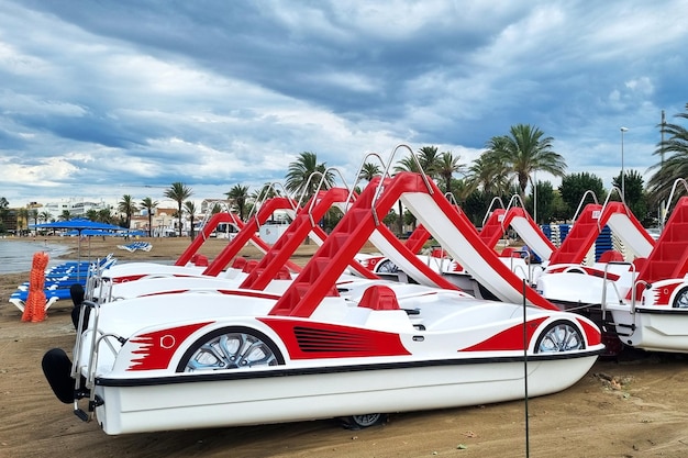 Catamarãs de prazer de plástico com slides de cor vermelha e branca na praia vazia na estância balnear