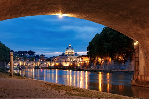 La Catedral de San Pedro y el puente de San Ángel sobre el río Tíber durante la hora azul de la mañana en Roma, Italia.