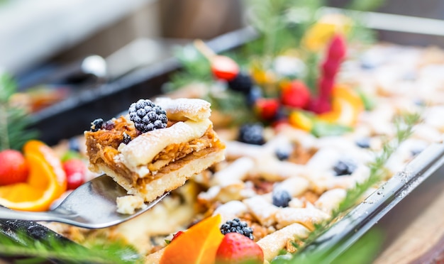 Catering comida buffet al aire libre. Tortas coloridas frutas frescas bayas naranjas uvas y decoraciones de hierbas.