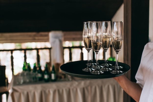 Catering-Service-Kellner bringt volle Gläser Champagner auf einem Tablettx9