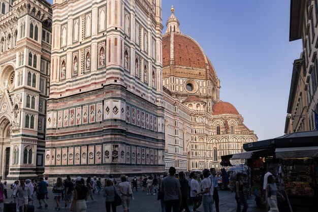 Foto cattedrale di santa maria del fiore à luz do pôr-do-sol com uma multidão de turistas a pé florença itália