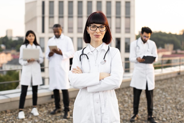 Foto caucasian doctor in white lab coat posing on camera with crossed hands