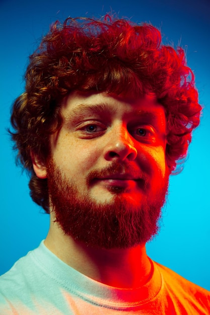 Foto caucasiano close-up retrato de homem isolado em fundo azul de estúdio em luz de néon