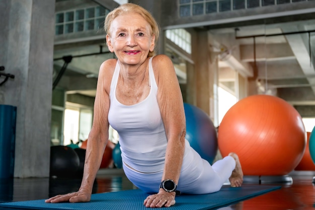 Foto caucasiano mulher sênior fazendo exercícios de ioga no ginásio.