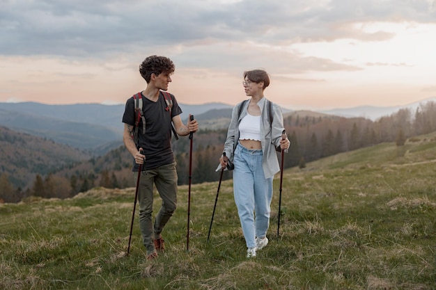 Caucasianos caminhantes de homem e mulher caminhando com bengalas nas montanhas com bela vista