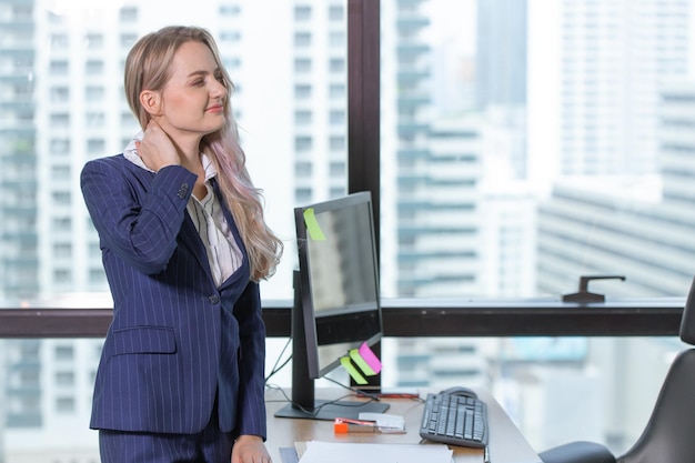 Caucasion mujer de negocios que sufre de síndrome de oficina gesto de dolor muscular de cuello