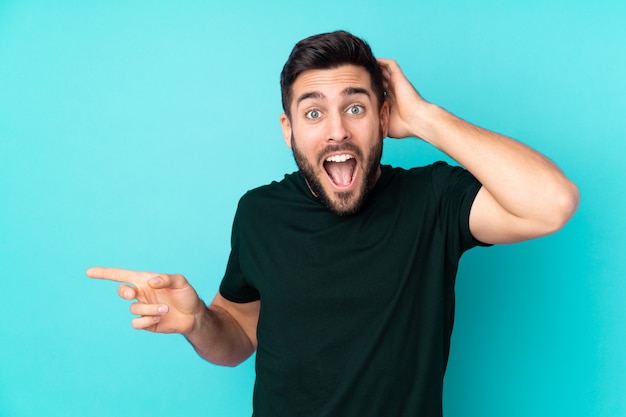 Foto cauchandsome hombre en azul sorprendido y apuntando con el dedo a un lado