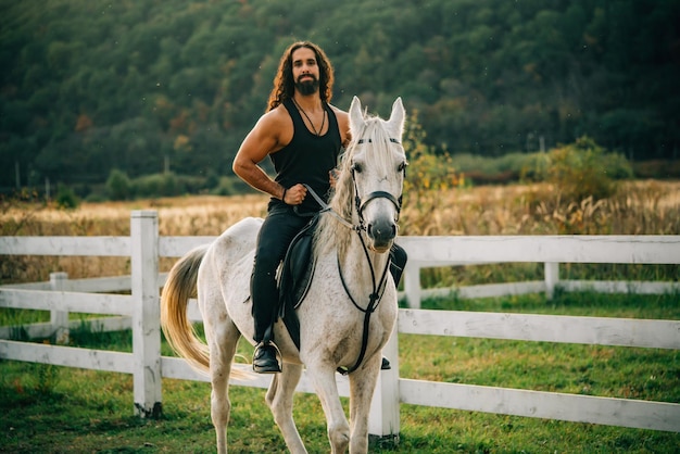 Cavaleiro do conceito de amor equestre e animal no cavalo árabe cinza no campo bonito homem barbudo livr ...