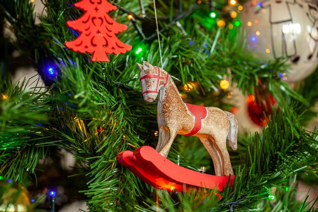 Cavalo de balanço pendurado na árvore de natal com bolas e luzes