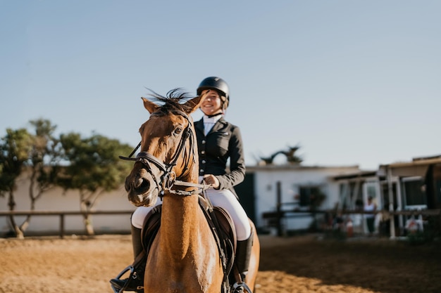 Cavalo marrom montado por amazona fora de foco