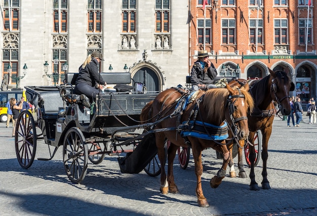 Cavalos e carruagens na Praça do Mercado de Bruges, Flandres Ocidental, na Bélgica