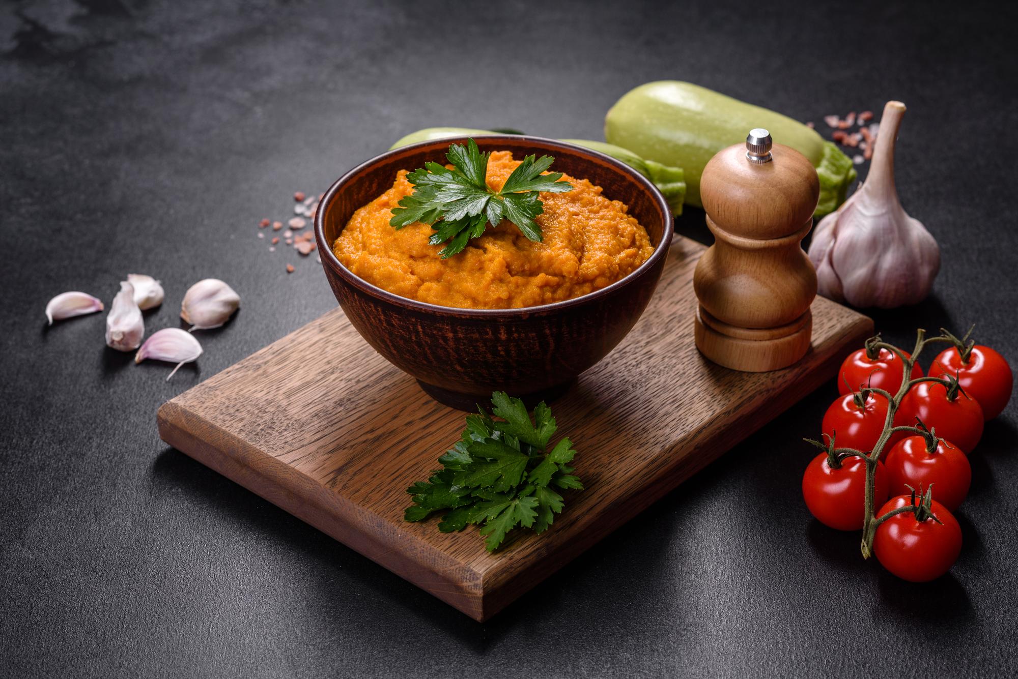 Caviar de calabaza con ajo y tomates en un bol rústico sobre un fondo oscuro