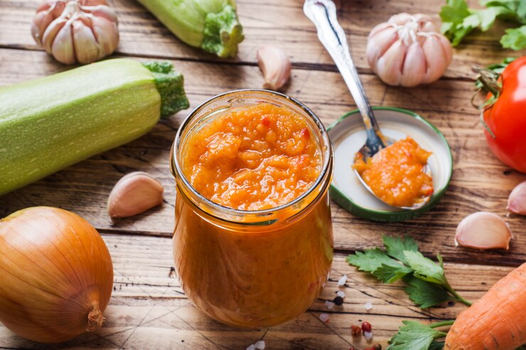 Caviar casero de calabacín tomates y cebollas en un frasco de vidrio sobre una mesa de madera Conservas caseras, conservas vegetales guisados.