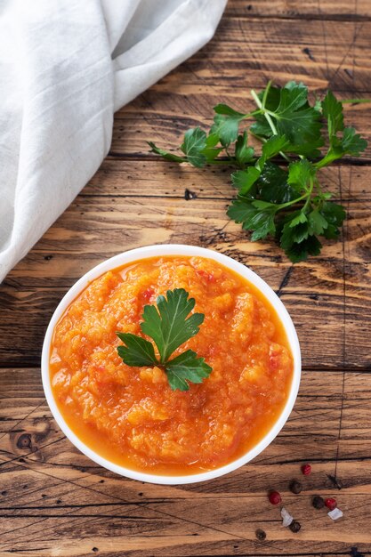 Caviar casero de calabacín, tomates y cebollas en una placa de cerámica sobre un fondo de madera. Conservas caseras de producción, conservas de verduras guisadas.