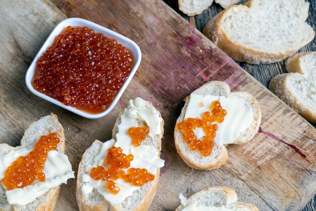 Caviar de salmão vermelho ou truta com baguete branca e manteiga fazendo sanduíches com manteiga de pão e caviar vermelho real