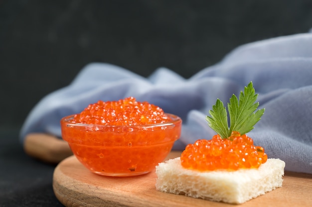 Foto caviar de salmão vermelho servido com pão e salsa na mesa de madeira