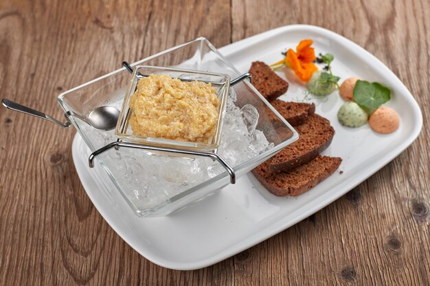 Caviar de lucio en un plato blanco con tostadas y hielo