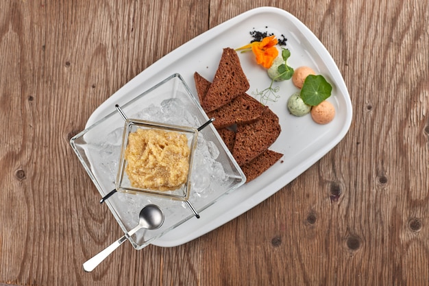 Caviar de lucio en un plato blanco con tostadas y hielo