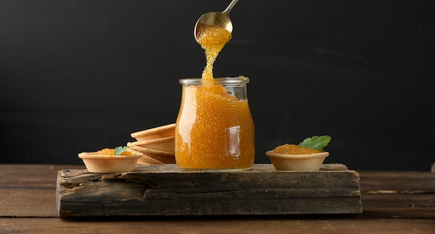 Caviar de lucio salado en un frasco de vidrio sobre una tabla de madera