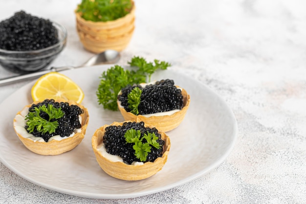 Caviar negro en tartaletas sobre un fondo claro. Concepto de comida sana. Copie el espacio.