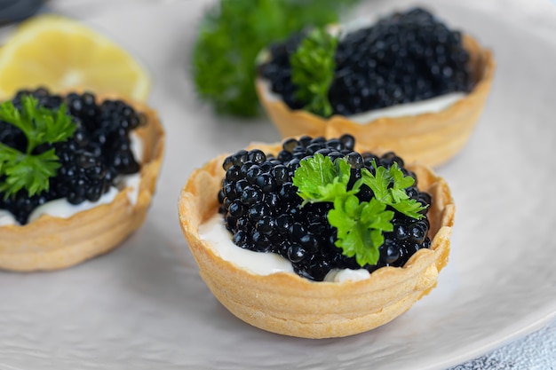 Caviar negro en tartaletas sobre un fondo claro. Concepto de comida sana. Copie el espacio.