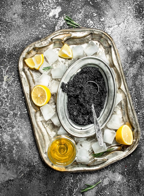 Caviar negro con vino blanco y rodajas de limón. Sobre fondo rústico.