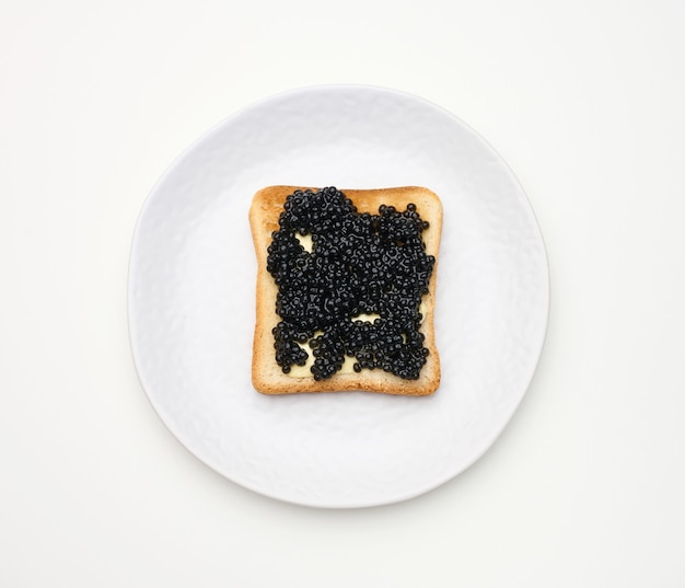 Caviar de pez espátula sobre una rebanada cuadrada de harina de trigo blanca. Vista superior de la mesa blanca