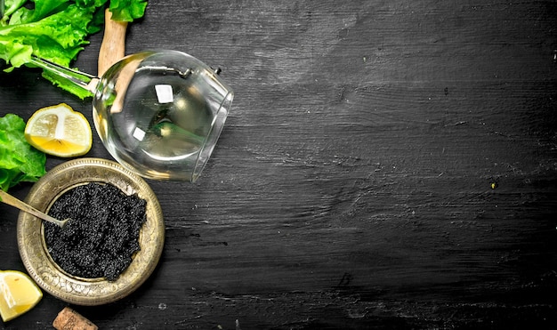 Caviar preto com vinho branco e ervas. em um quadro negro.