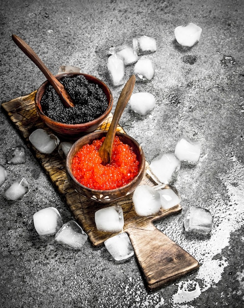 Foto caviar preto e vermelho em uma tigela na velha placa. sobre fundo rústico.