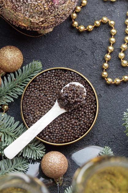 Caviar preto em uma colher de madrepérola com decoração de Natal