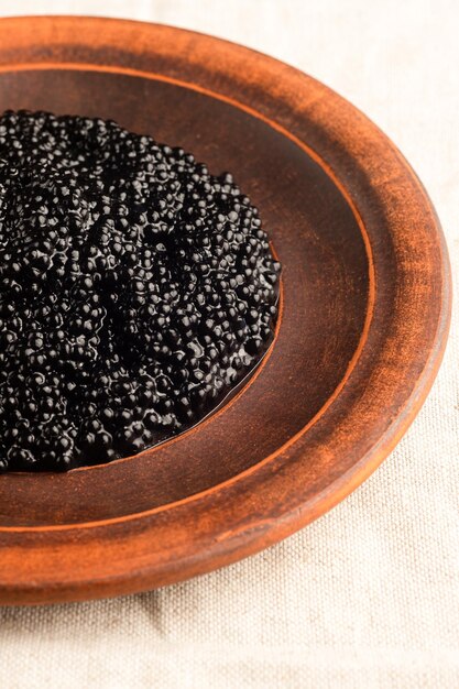 Caviar preto em uma placa de madeira. Close-up de caviar. Iguarias. Comida deliciosa. A textura do caviar. Frutos do mar.