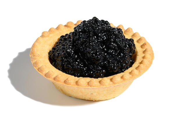 Caviar preto em uma tortinha redonda sobre um fundo branco e isolado