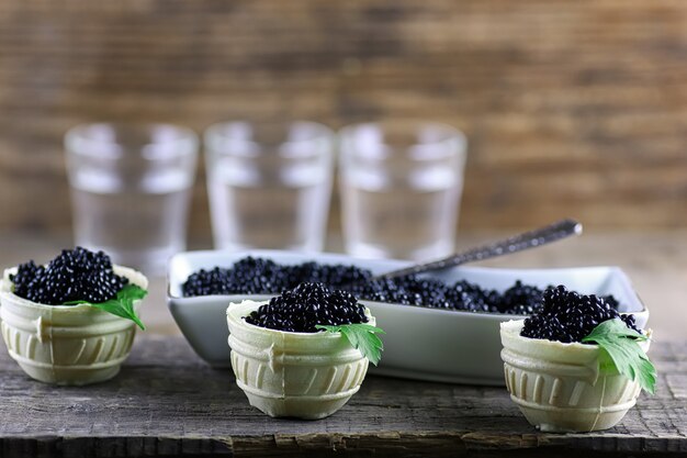 Caviar preto na porção em um fundo de madeira